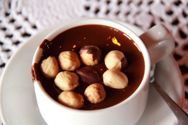 Hot chocolate with nuts in a white cup on a brown table — Stock Photo, Image