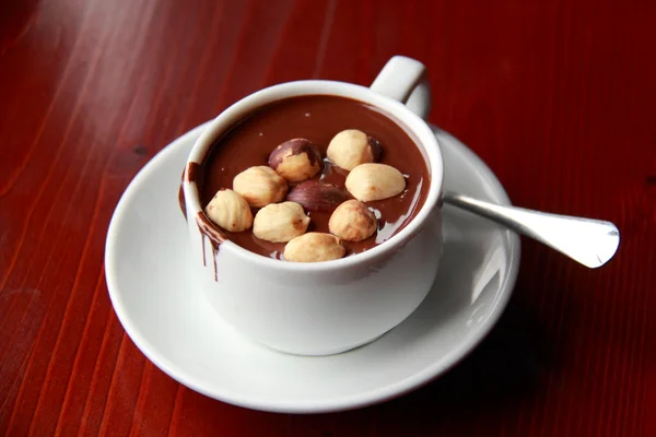 Hot chocolate with nuts in a white cup on a brown table — Stock Photo, Image