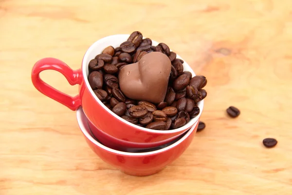 Dva šálky s kávová zrna a čokoládové bonbóny — Stock fotografie