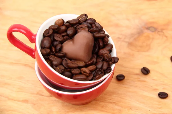 Deux tasses avec des grains de café et des bonbons au chocolat — Photo