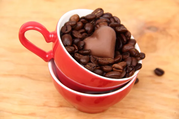 Deux tasses avec des grains de café et des bonbons au chocolat — Photo