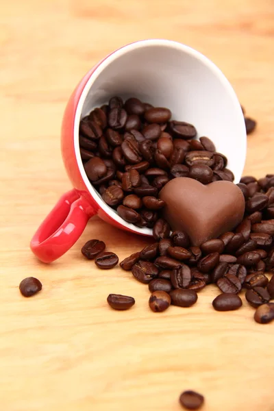 Чашка с кофейными зёрнами и шоколадной конфеткой — стоковое фото