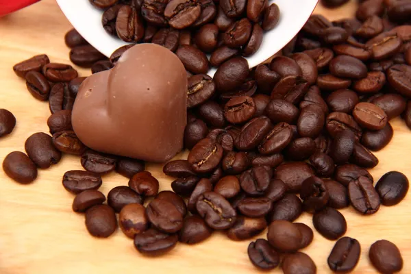 Чашка с кофейными зёрнами и шоколадной конфеткой — стоковое фото