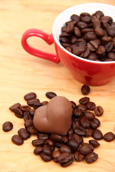 Cup with coffee beans and chocolate candy — Stock Photo, Image