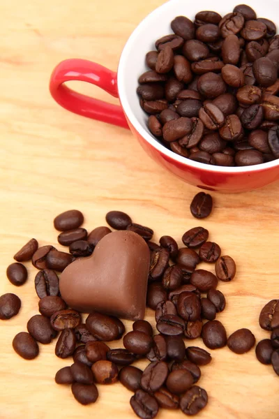 Cup with coffee beans and chocolate candy — Stock Photo, Image
