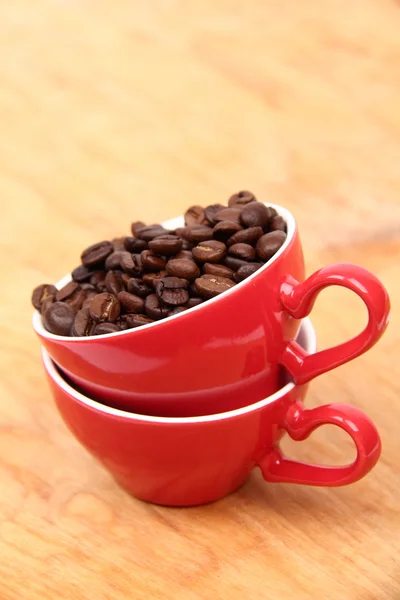 Dos tazas de café rojo con granos de café —  Fotos de Stock