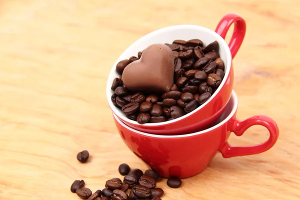 Две чашки с кофейными зёрнами и шоколадными конфетками — стоковое фото