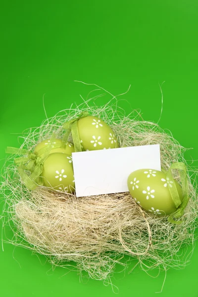Пасхальные яйца в гнезде с карточкой — стоковое фото