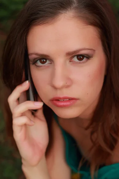 Menina em um vestido verde segurando um celular — Fotografia de Stock