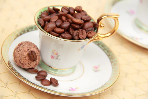 Coffee beans in cup and saucer — Stock Photo, Image