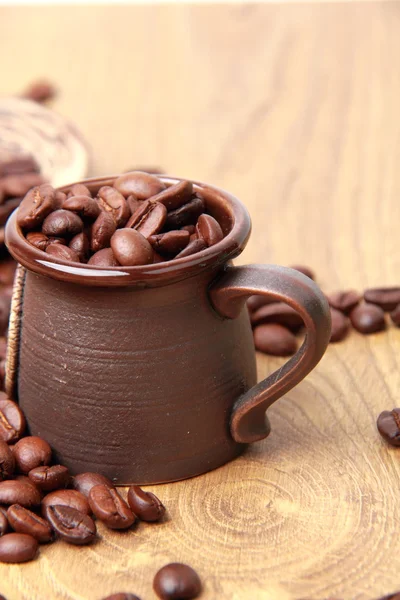 कुंभारकामविषयक कॉफी कपमध्ये स्वादिष्ट तपकिरी कॉफी बीन्स — स्टॉक फोटो, इमेज