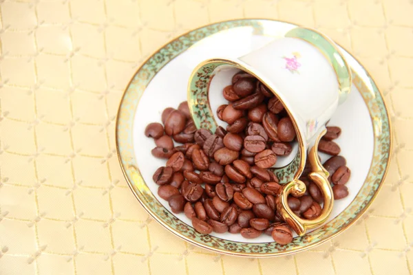 Xícara de café cheia de grãos de café na toalha de mesa — Fotografia de Stock