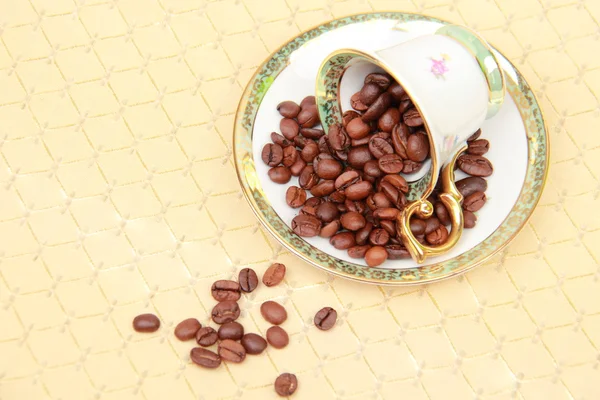 Kahve fincanı kahve çekirdekleri masa örtüsü üzerinde dolu — Stok fotoğraf