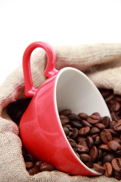 Granos de café en taza de café rojo con símbolo del corazón sobre el saco de arpillera —  Fotos de Stock