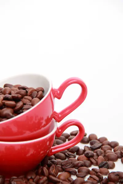 Granos de café en taza roja con símbolo del corazón —  Fotos de Stock