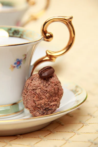 Klassieke koffie beker vol met koffiebonen en snoep op het tafellaken — Stockfoto