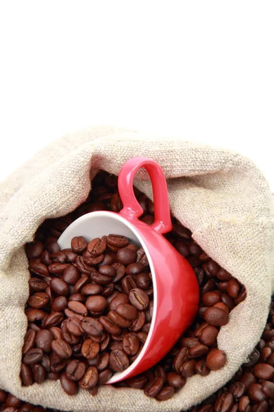 Granos de café en taza roja con símbolo del corazón sobre el saco de arpillera —  Fotos de Stock