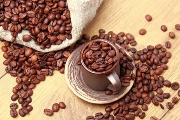 Biji kopi coklat gelap dengan cangkir kopi keramik dan karung — Stok Foto