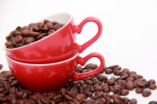 Grains de café en tasse rouge avec symbole de coeur — Photo