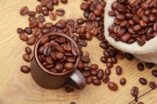 Chicchi di caffè marrone scuro con tazza di caffè e sacco — Foto Stock