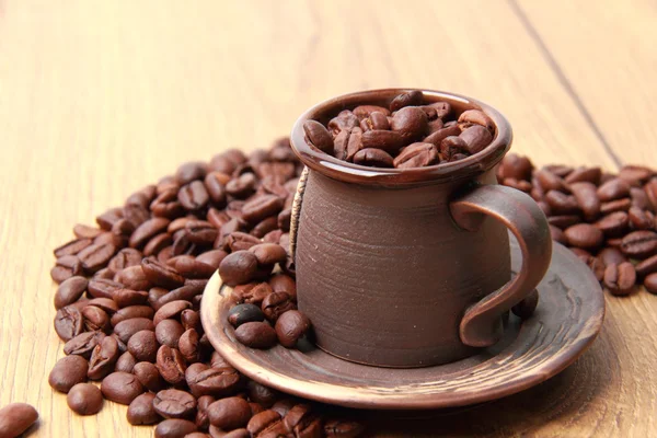 Delicious dark brown coffee beans in small ceramic cup — Stock Photo, Image