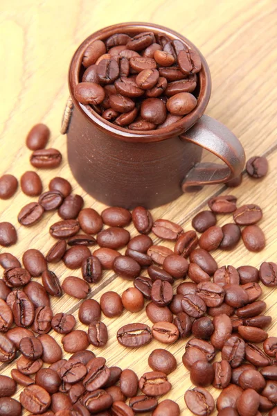Вкусные темно-коричневые кофейные зерна в небольшой керамической чашке — стоковое фото