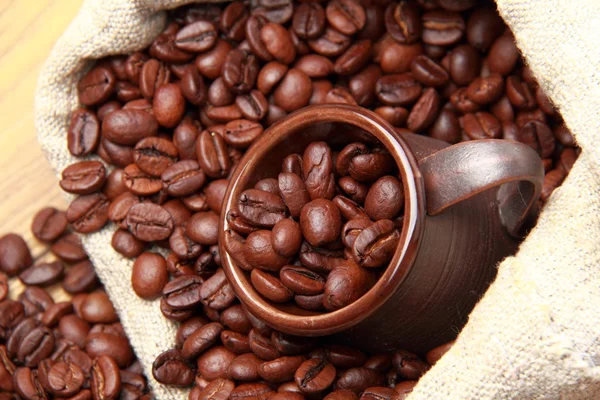 Kacang kopi panggang dengan cangkir kopi keramik di atas selempang goni — Stok Foto