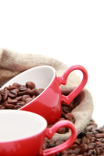 Grãos de café em copo vermelho com símbolo de coração sobre saco de serapilheira — Fotografia de Stock