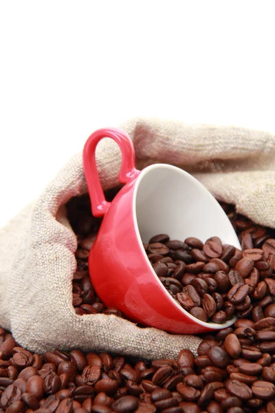 Grãos de café em copo vermelho com símbolo de coração sobre saco de serapilheira — Fotografia de Stock