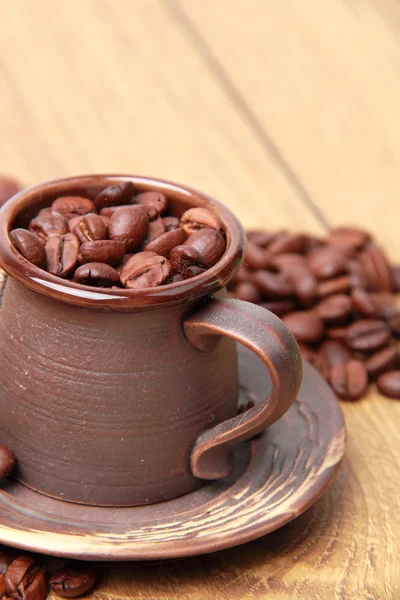 लहान कुंभारकामविषयक कॉफी कपमध्ये स्वादिष्ट गडद तपकिरी कॉफी बीन्स — स्टॉक फोटो, इमेज