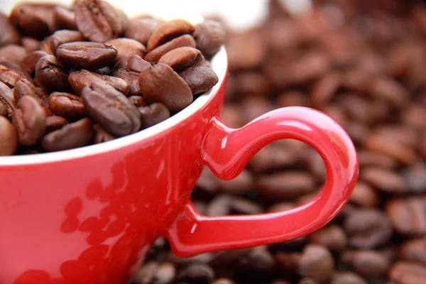 Granos de café en taza roja con símbolo del corazón —  Fotos de Stock