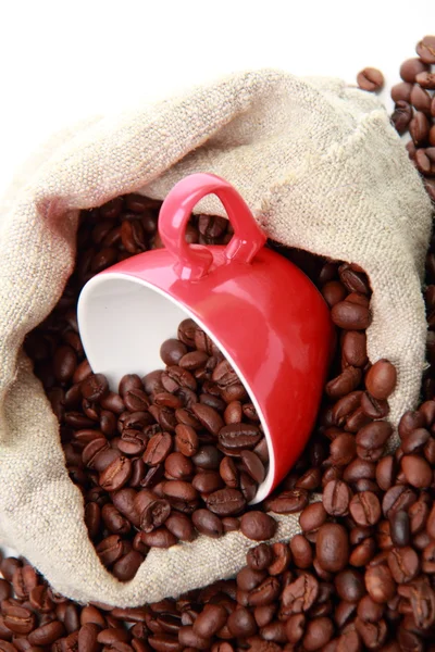 Granos de café en taza roja con símbolo del corazón sobre el saco de arpillera —  Fotos de Stock