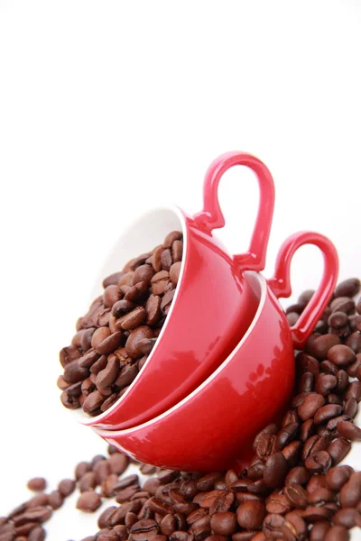 Grãos de café em copo vermelho com símbolo de coração — Fotografia de Stock