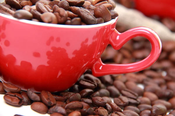 Grãos de café em copo vermelho com símbolo de coração — Fotografia de Stock