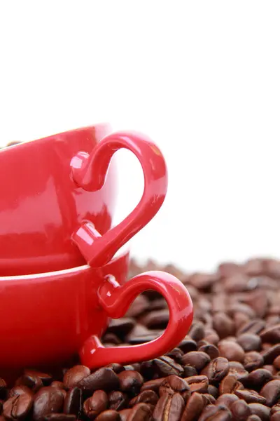 Grãos de café em copo vermelho com símbolo de coração — Fotografia de Stock