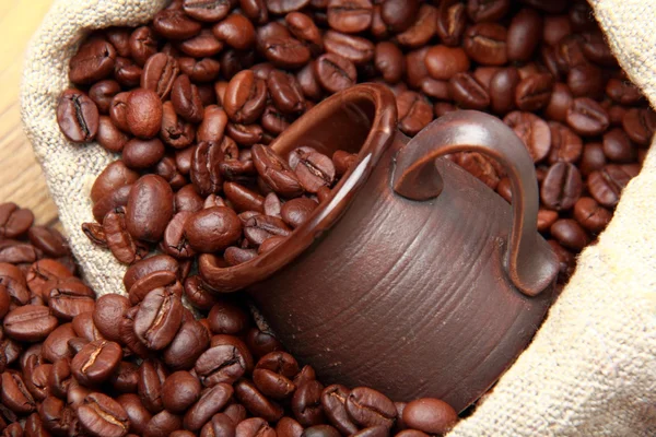 Chicchi di caffè torrefatto con tazza di ceramica sopra sacchetto di caffè iuta — Foto Stock