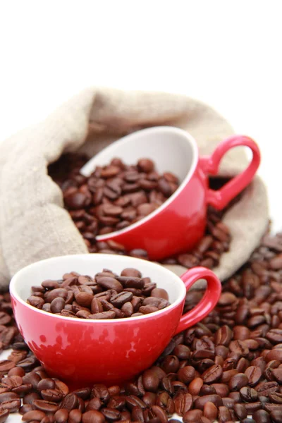 Granos de café en taza roja con símbolo del corazón sobre el saco de arpillera —  Fotos de Stock