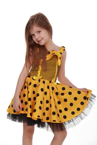 Charming emotional little girl in a yellow dress — Stock Photo, Image