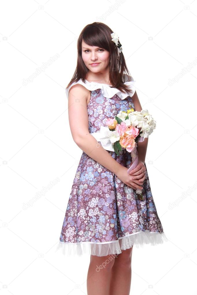 Charming young woman with dark hair in a beautiful dress holding a bouquet of flowers