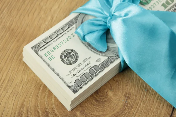 One hundred dollars gift pack isolated on wooden background — Stock Photo, Image