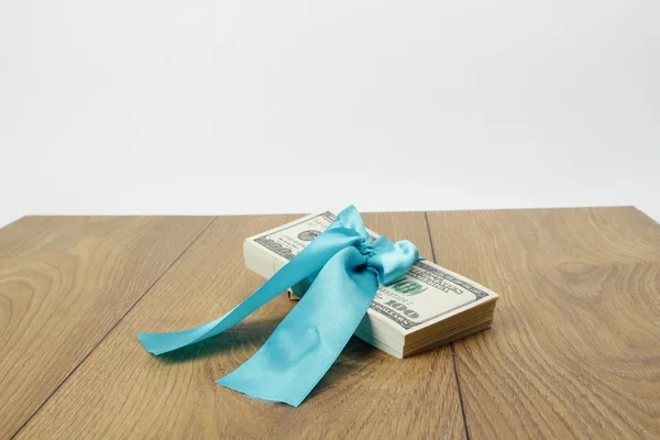 Pacote de presente de cem dólares isolado na mesa de madeira — Fotografia de Stock