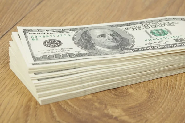 Stack of hundred-dollar bills on wooden background — Stock Photo, Image