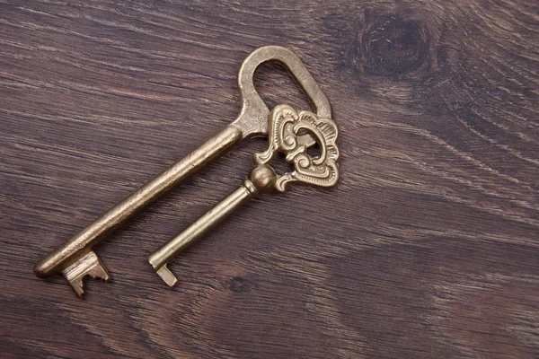 Two ancient keys with ornament on dark wooden background — Stock Photo, Image