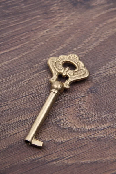 Old key with ornament on dark wooden background — Stock Photo, Image