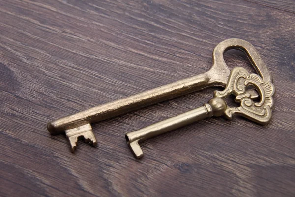 Two ancient keys with ornament on dark wooden background — Stock Photo, Image