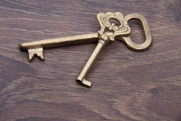 Zwei antike Schlüssel mit Ornament auf dunklem Holzgrund — Stockfoto