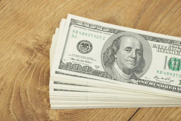 Stack of hundred-dollar bills on wooden background — Stock Photo, Image