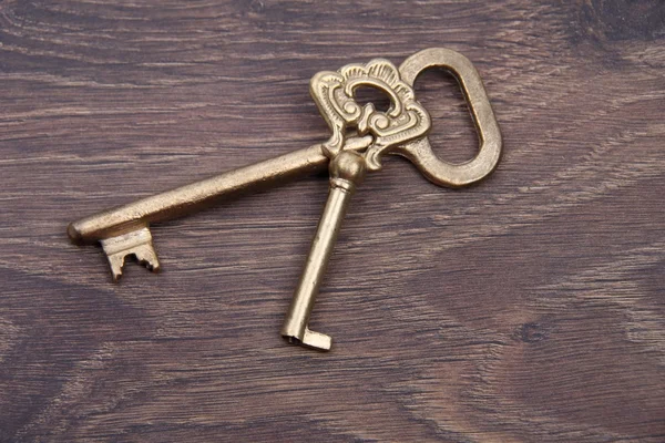 Koyu ahşap zemin üzerinde süsleme ile iki eski anahtar — Stok fotoğraf