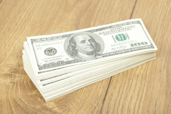 Montón de billetes de cien dólares sobre fondo de madera — Foto de Stock