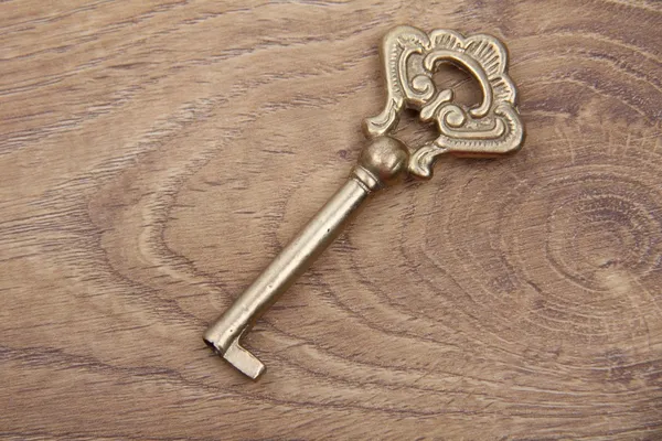 Ancient key with ornament on wooden background — Stock Photo, Image